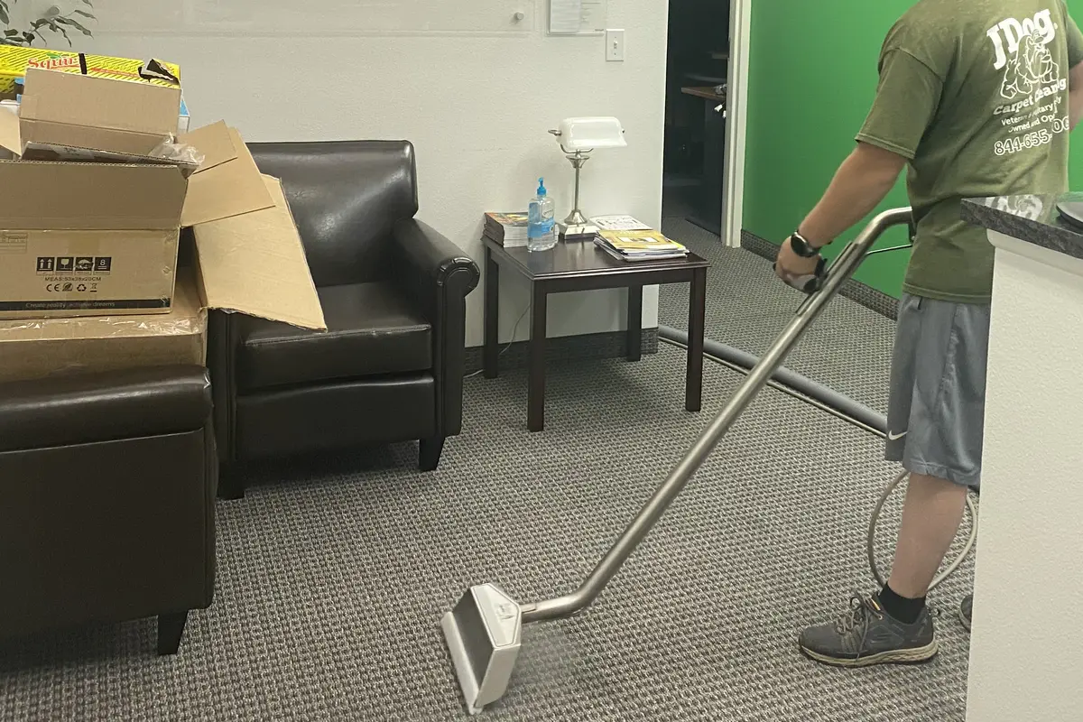 JDog technician running a carpet extraction wand across the carpet in a St. George area office